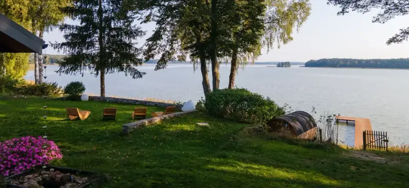 Taras z leżakami nad jeziorem, z widokiem na las i pomost.