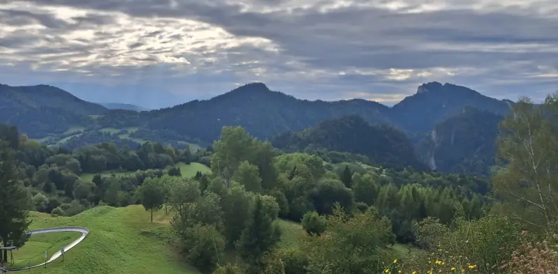 Krajobraz górski z wąwozem, lasami i torami saneczkowymi w tle.